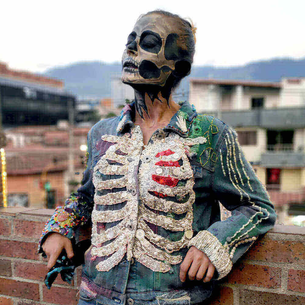 Dua Tua wearing the "Bones Jacket" on a rooftop in Medellin, with her face painted by BIMANA FX to resemble a skull.