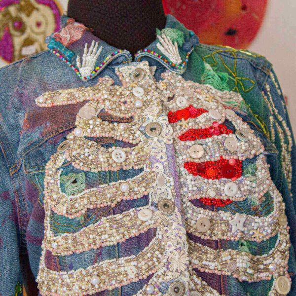 Front view of the "Bones Jacket" showcasing the details of the resin hands on the collar and the white rib design created with beads.