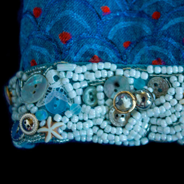 Close-up detail of the cuff of the Pulpis jacket decorated with white beads and buttons of different sizes and shapes embroidered onto the denim