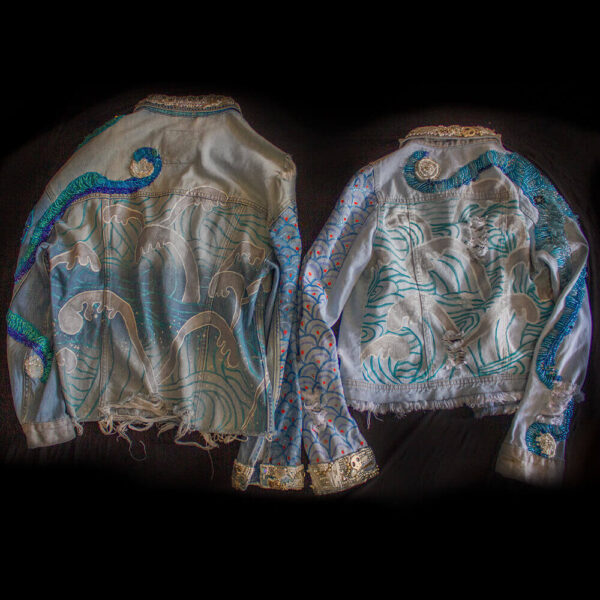 Back view of both Pulpis denim jackets with hand-painted waves at the back and beaded embroidered tentacles in various shades of blue. The jackets also showcase painted texture on the arms, as well as ripped fabric in certain areas.