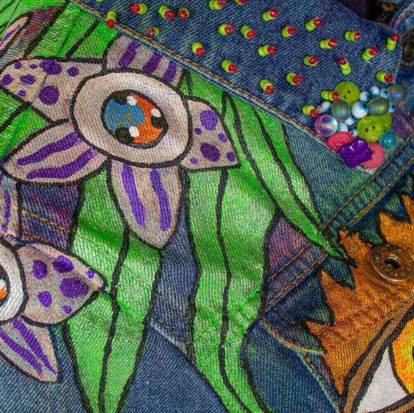 Shoulder close-up of the front of the jacket with the cyclop purple flower, a creature of the Dua Tua forest, showcasing the beaded texture in the collar