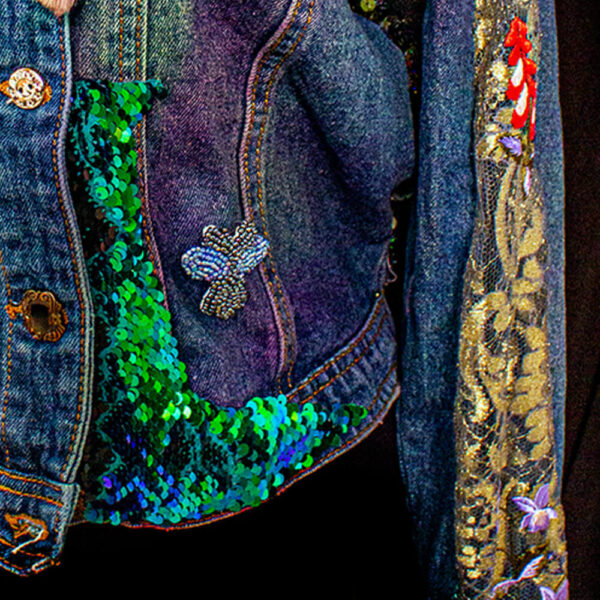 Front view detail of the Botanica Bugs Jacket, featuring a sequin texture at the bottom and golden lace on the arms.