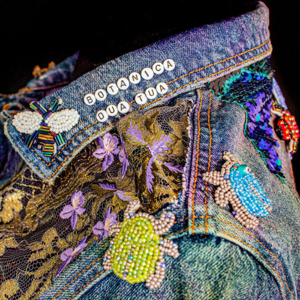 Collar detail of the Botanica Bugs Jacket, featuring insect bead patches and golden lace on the shoulders