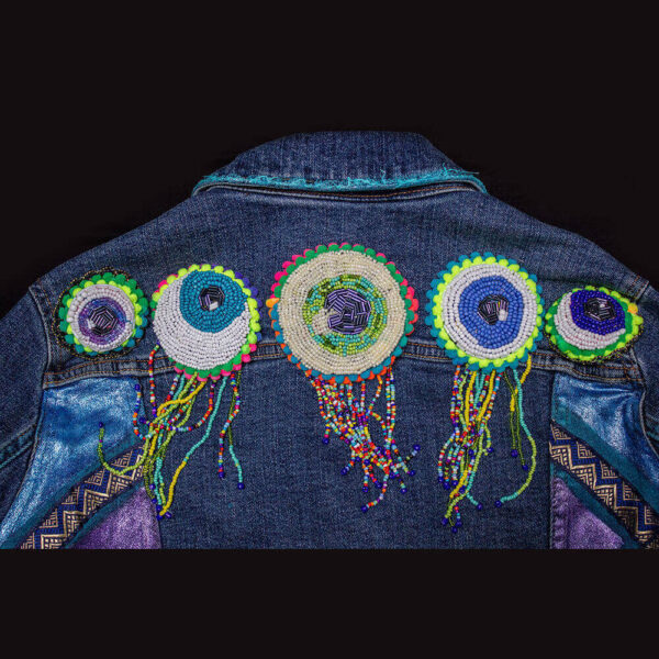 Detail of the five beaded eye patches featuring white, blue, green, and colorful beads on the "I See You Jacket."