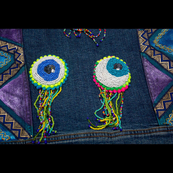 Close-up detail of the beaded eye patches on the "I See You Jacket."