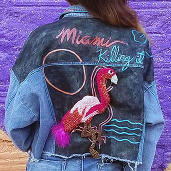 Back view of a model wearing the "Miami Vice" jacket adorned with a flamingo bead patch.