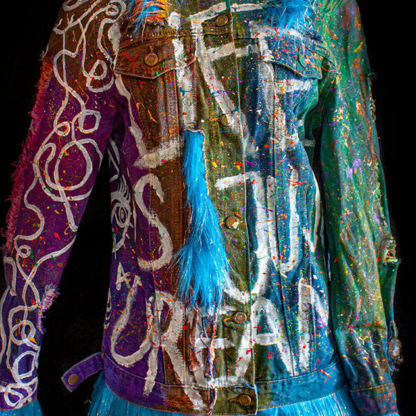 Close-up of the front of the Alien denim jacket, highlighting the hand-painted letters on the jacket and the added furry textiles