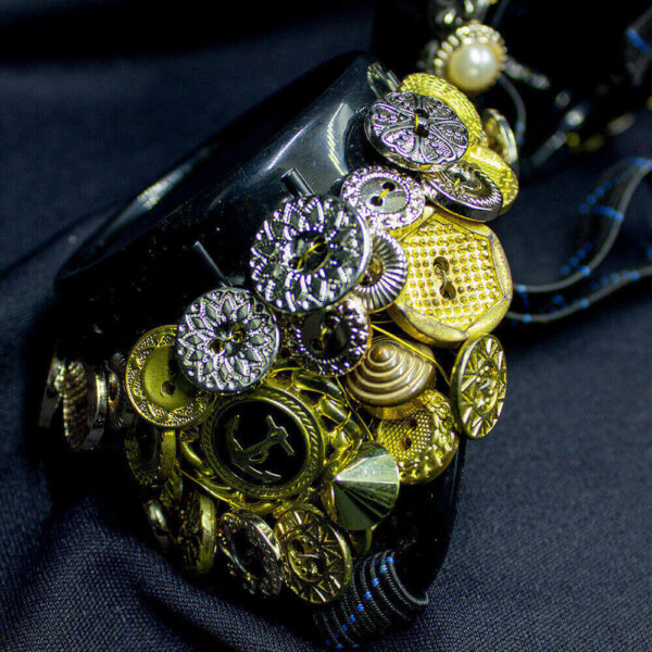 Close-up detail of the Golden goggles, highlighting the various golden buttons with different shapes and styles that are intricately woven with wire