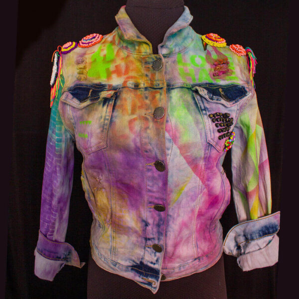 Front view of the Trippy Dragon denim jacket with a tie-dye effect and text stencil texture in vibrant acid colors, including purple, green, and yellow