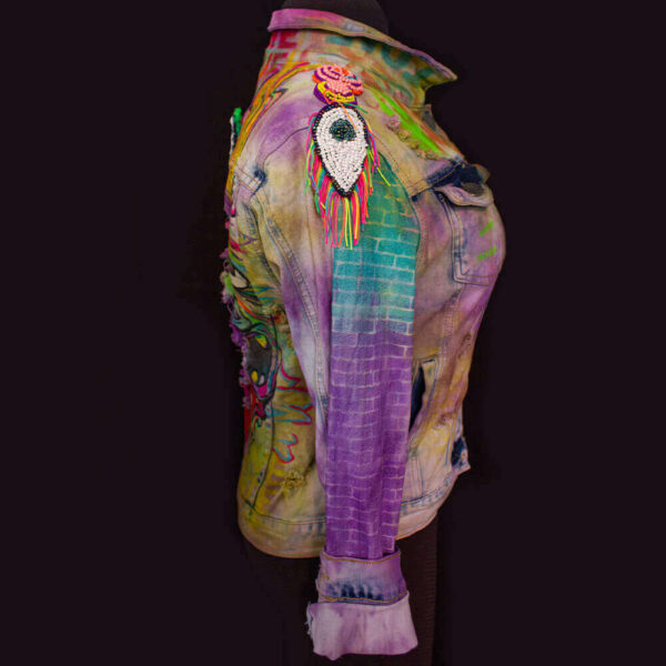 Right view of the Trippy Dragon denim jacket featuring purple and light blue neon stencil-painted texture on the arm, with a removable drop-shaped eye beaded patch on the shoulder