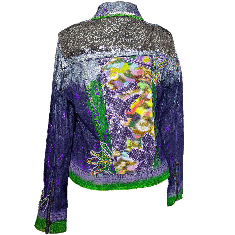 Back view of the Botanica Purple Denim Jacket. The jacket is adorned with vivid purple and green colors. Transparent sequins are added at the shoulder height across the back, while the middle features fabrics resembling sequins and colorful textures. It is hand-painted with 3D paint creating intersecting lines across the jacket. Additionally, embroidered flowers made with beads are sewn onto the jacket