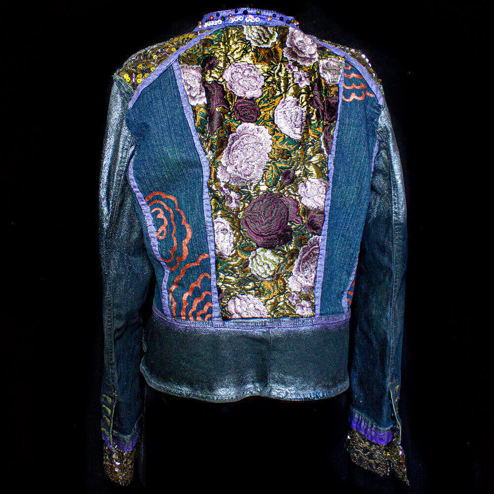 Back view of the Botanica Roses Denim Jacket showcasing delicate floral lace fabric on the back, hand-painted red rose texture, and golden sequin fabric on the shoulders and cuffs