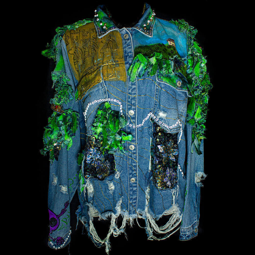 Front view of the Diana Uribe Customized Denim Jacket adorned with denim scraps, fabric sequins, 3D golden paint, details as a hieroglyphs drawing, details made with fabric paint and letter beads