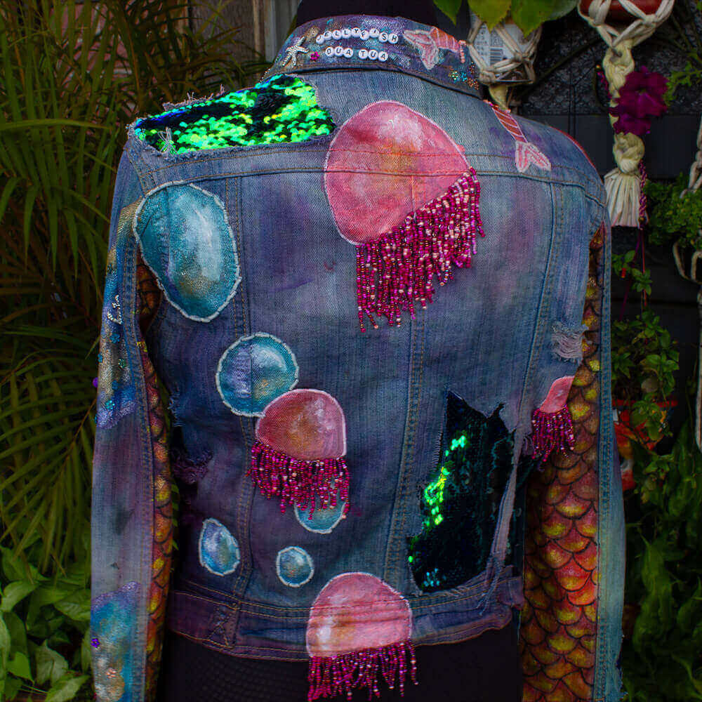 Back view of the Jellyfish denim Jacket, adorned with hand-painted jellyfish, sparkling sequins fabric on details, pink bead textures and scales paint texture on sleeves