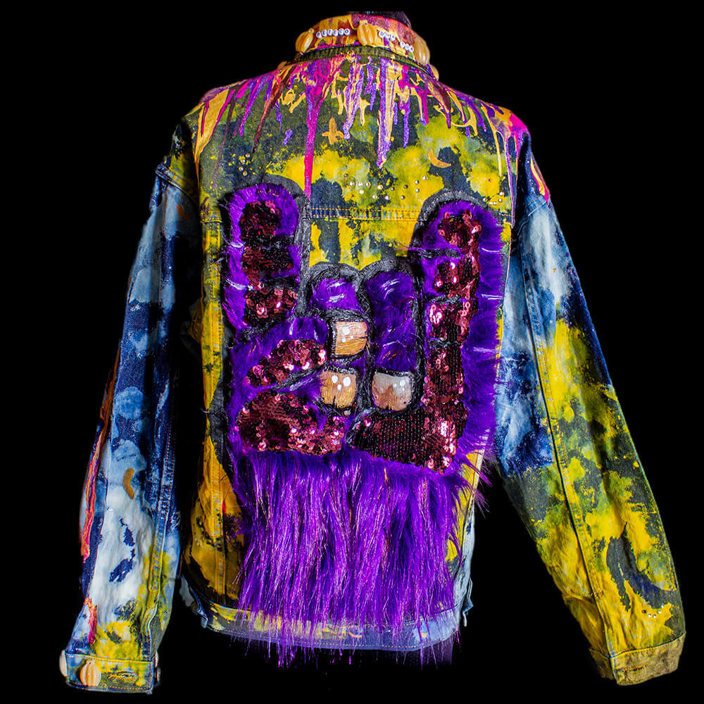 Back view of the Kong denim jacket made with furry fabric monkey hand with resin nails, sequin texture fabric and fabric paint, bleach on denim, resin banana decoration all over the jacket and fake crystals