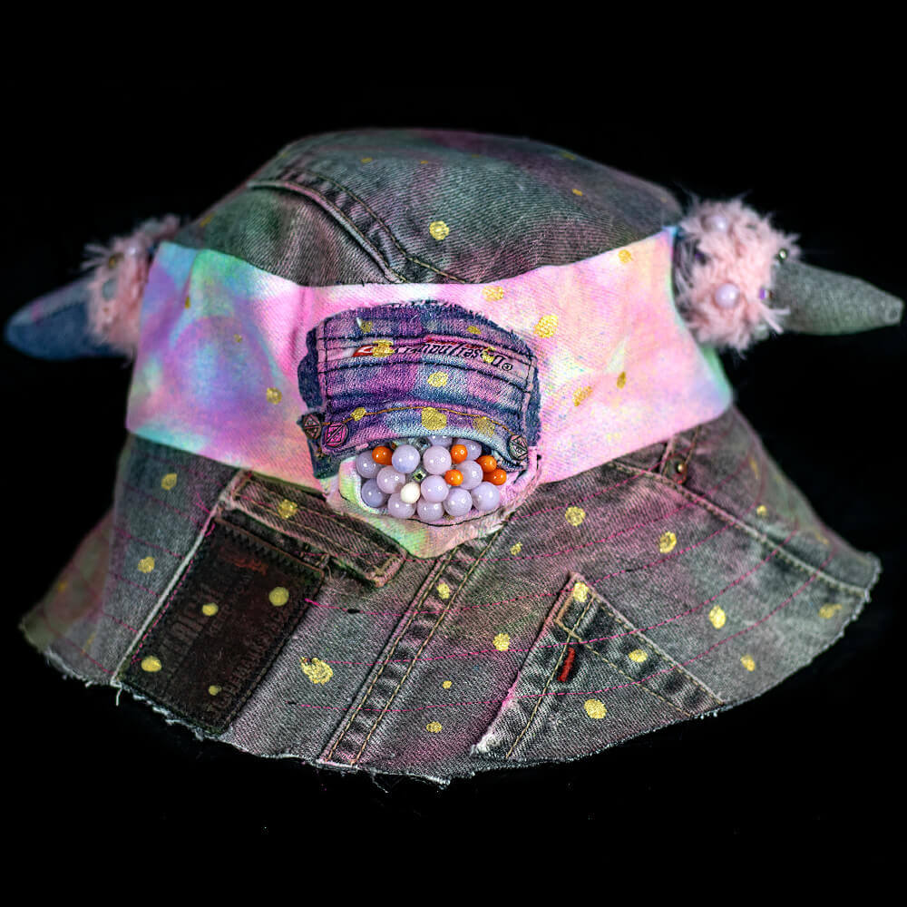 Front view of the MXD Pink bucket hat made from upcycled denim scrap, spray paint texture, golden paint dots, with furry accents on the denim horns and a Cyclop beaded eye