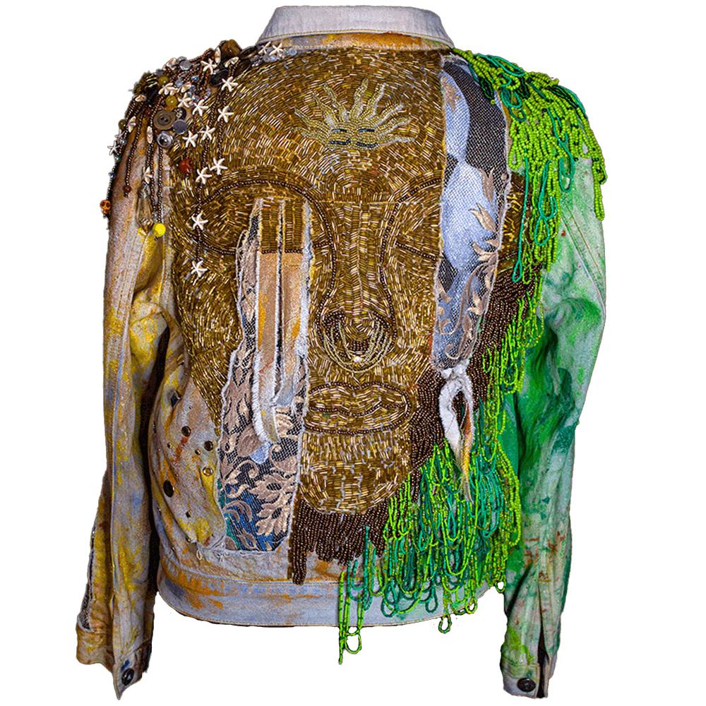 Back view of an embroidered face created for the Quimbaya denim jacket made with large gold-color beads, round gold-color beads and fabric paint. Details on shoulders and sides including beads, recycle buttons and accessories