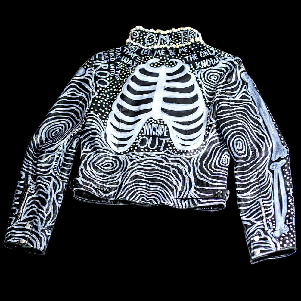 Back view of the Ribs leather jacket decorated with leather paint ribs drawings and texts, embroidered rounded beads and accessories on the collar and 3D paint details