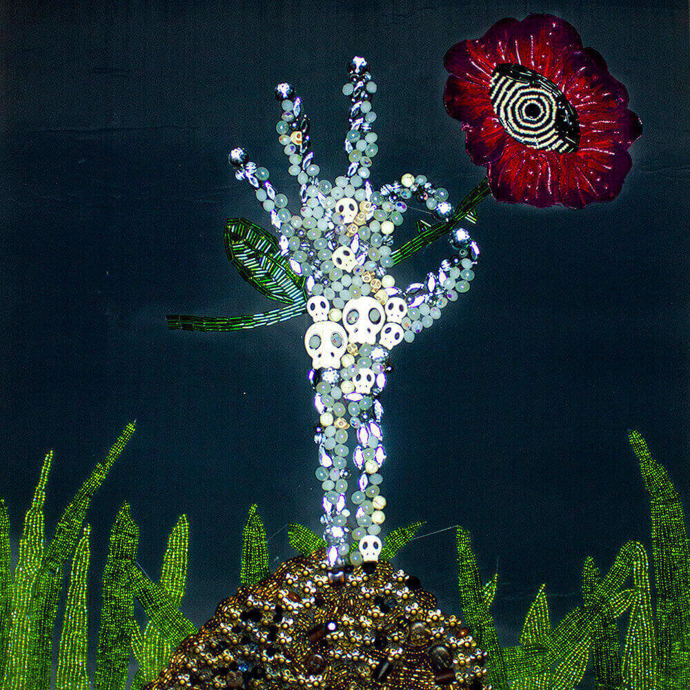 Close-up detail middle front view of the Skeleton Flower embroidered frame decorated with skeleton hand shape made with beads, buttons, accessories, fabric paint, 3D paint and denim scraps for the flower detail