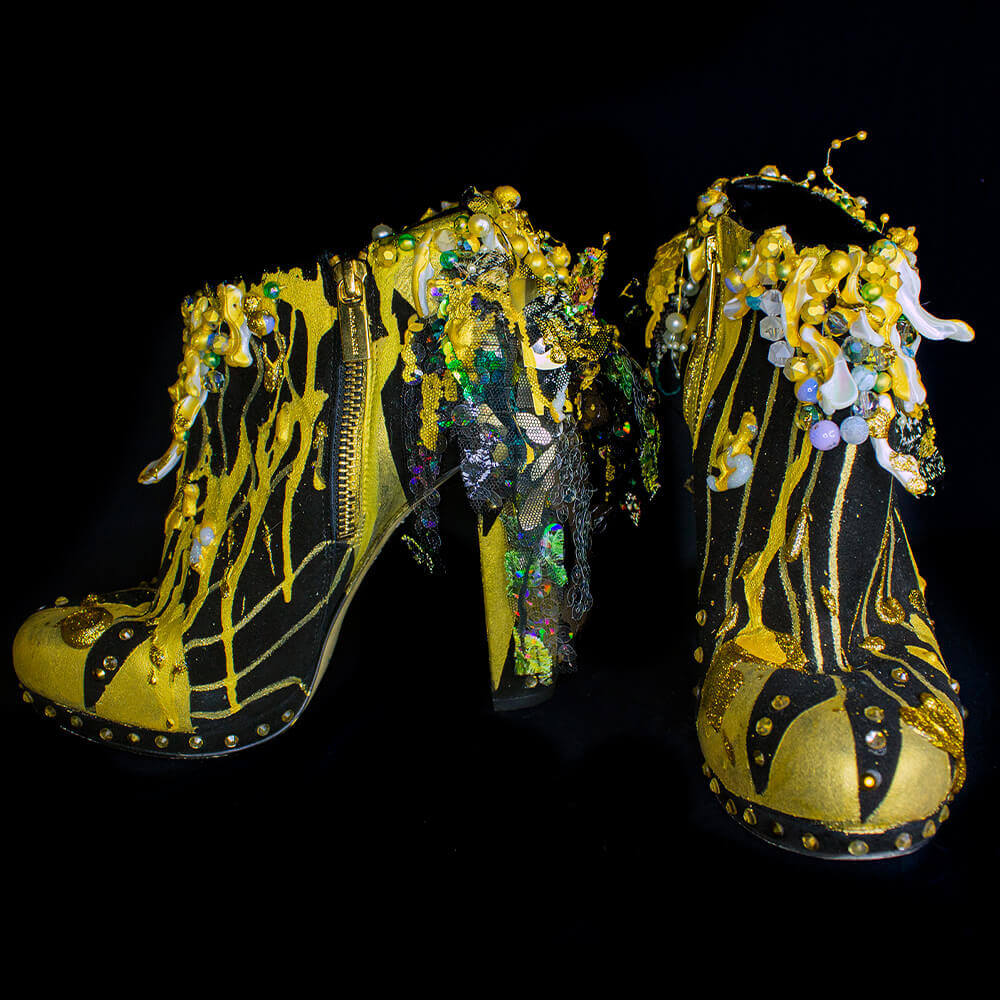 - Front view of the Golden sun heeled booties, featuring golden-black, 3D paint, sequins and laces, decorative accessories and embroidered beads