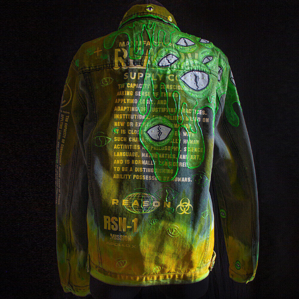 Back view of the Toxic denim jacket decorated with neon green and yellow hues, alien eyes, silk-screened text on the back and 3D paint details