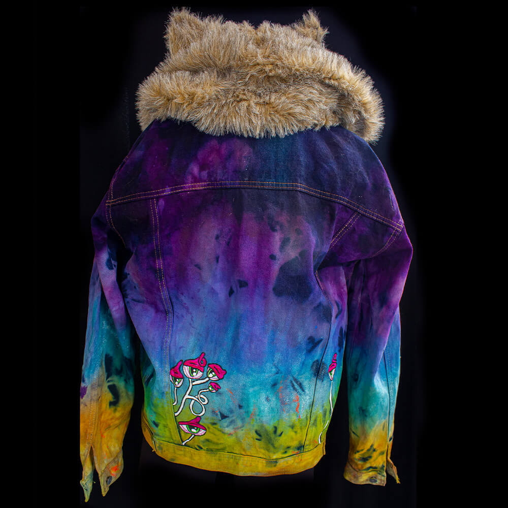 Back view of the Trip hooded denim jacket decorated with synthetic furry fabric for the hood (with ears) a color gradient texture all over the garment and some hand-painted cyclops mushrooms