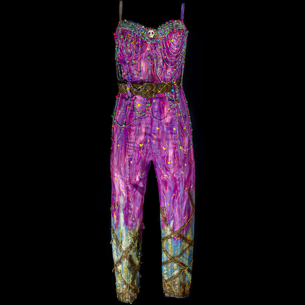 Front view of the Candy denim jumpsuit decorated with pink/purple fabric paint on top and brown and gold on the bottom, 3D paint and embroidered colorful beads all over the top and middle of the garment, and a brown belt