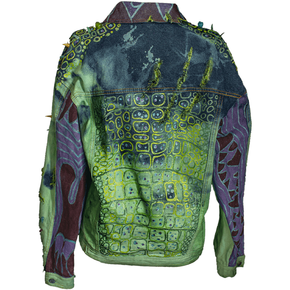 General back view of the Coco denim jack with a ripped mark on the back upper-right, a hand painted cocodrile-skin texture on the back, sleeves and collar, decorated with resin fangs and bird skulls on shoulders