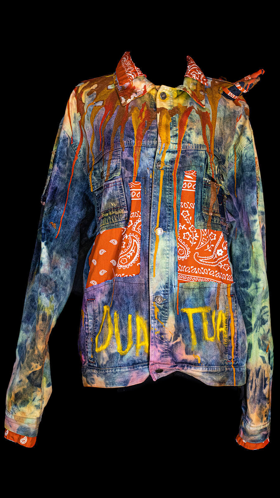 Upcycled Tom Papa Denim Jacket: Colorful Fabric Patches & Drip Art. This unique jacket features vibrant fabric inserts, handcrafted denim cone spikes (back & left shoulder), and a creative dripping paint design